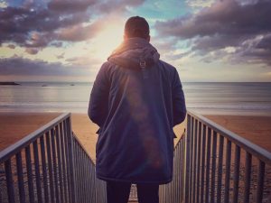 Man Standing on Stairs Looking Out Onto Beach
