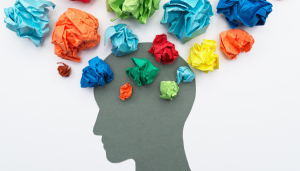 Silhouette of a human head with colorful crumpled paper balls above and inside, symbolizing thoughts, ideas, or mental activity.